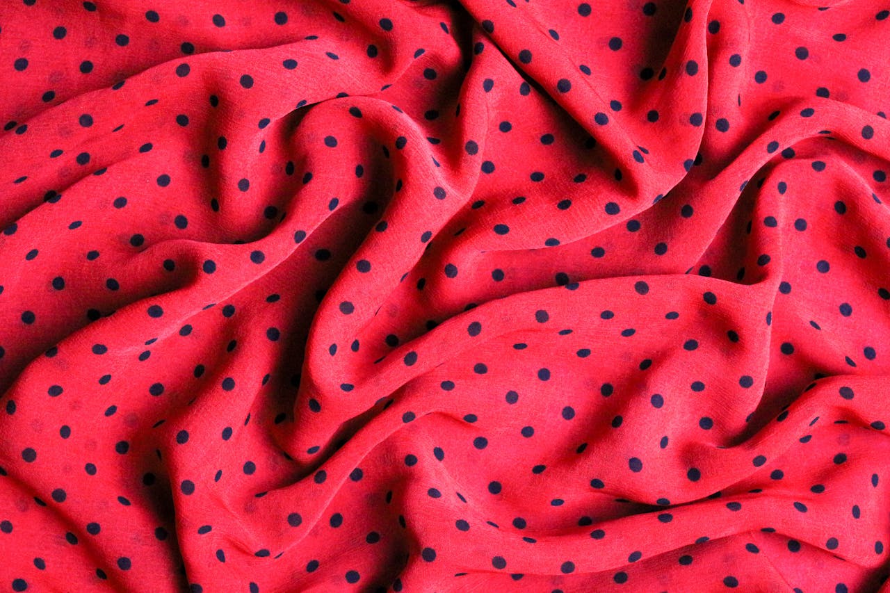 Close-up of red polka dot fabric with textured folds and vibrant colors.